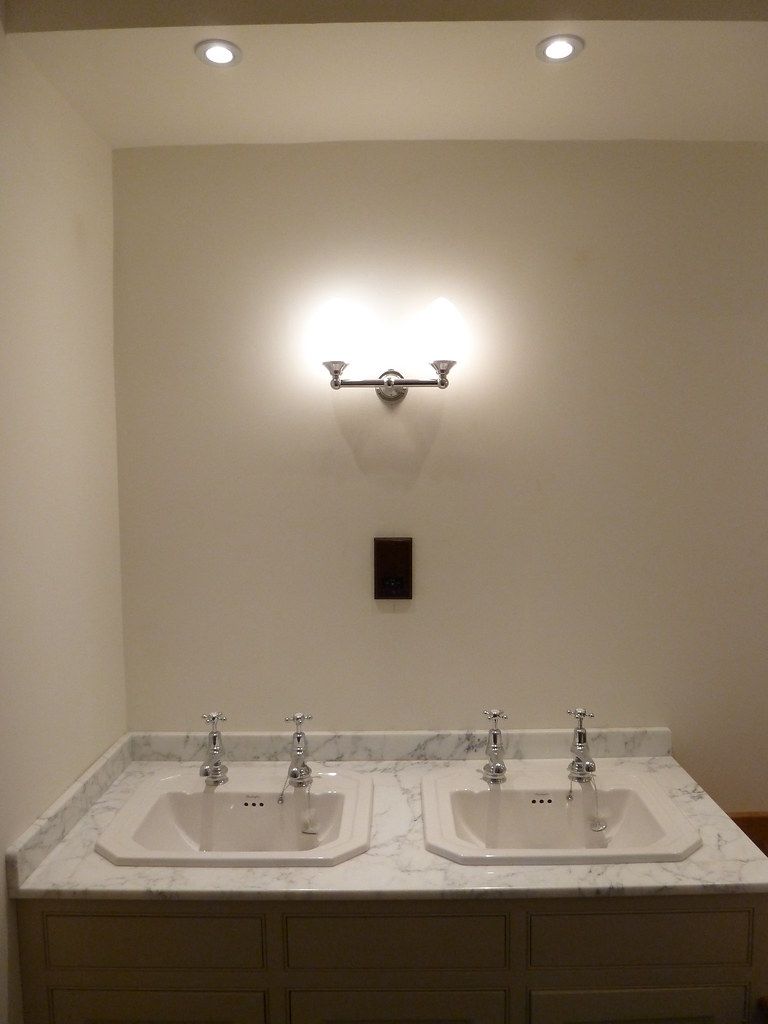 Bathroom with twin basins, a twin-arm wall light and recessed ceiling downlights