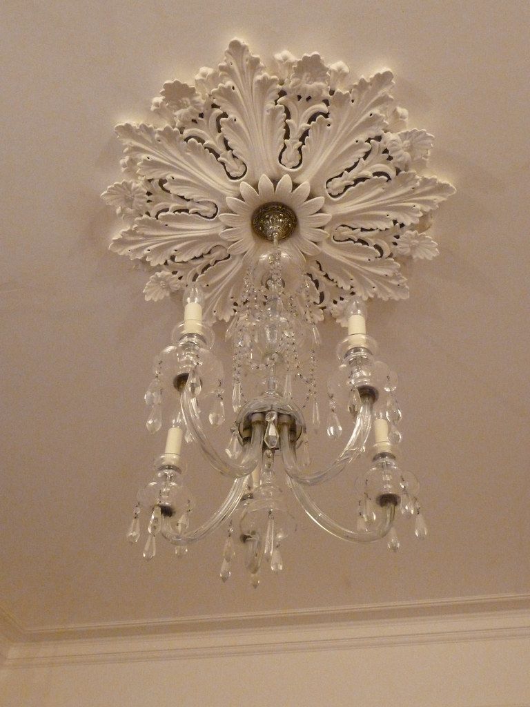 Crystal candle-arm chandelier hanging from an ornate plaster ceiling rose
