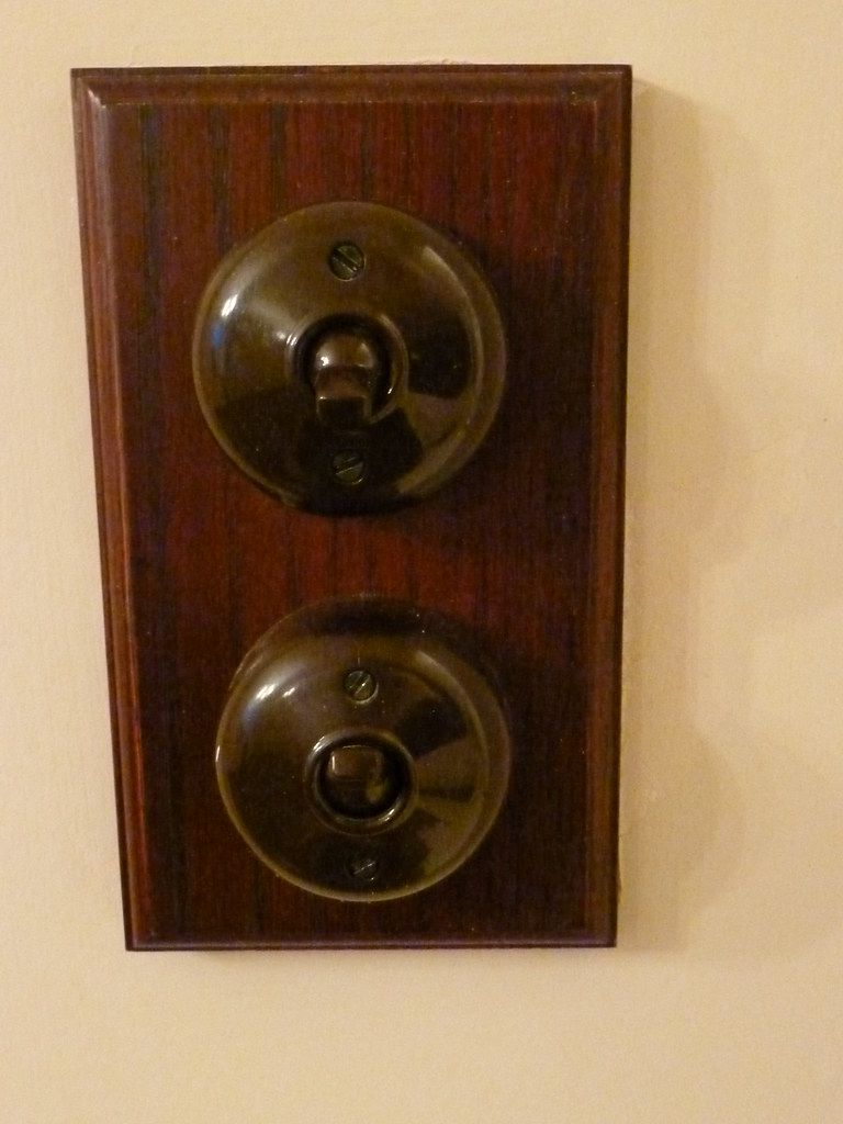 Two brass switches on a tall wooden pattress